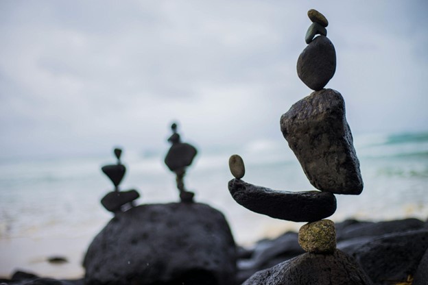 Stones artistically stacked and balanced on a rocky beach with the ocean blurred in the background